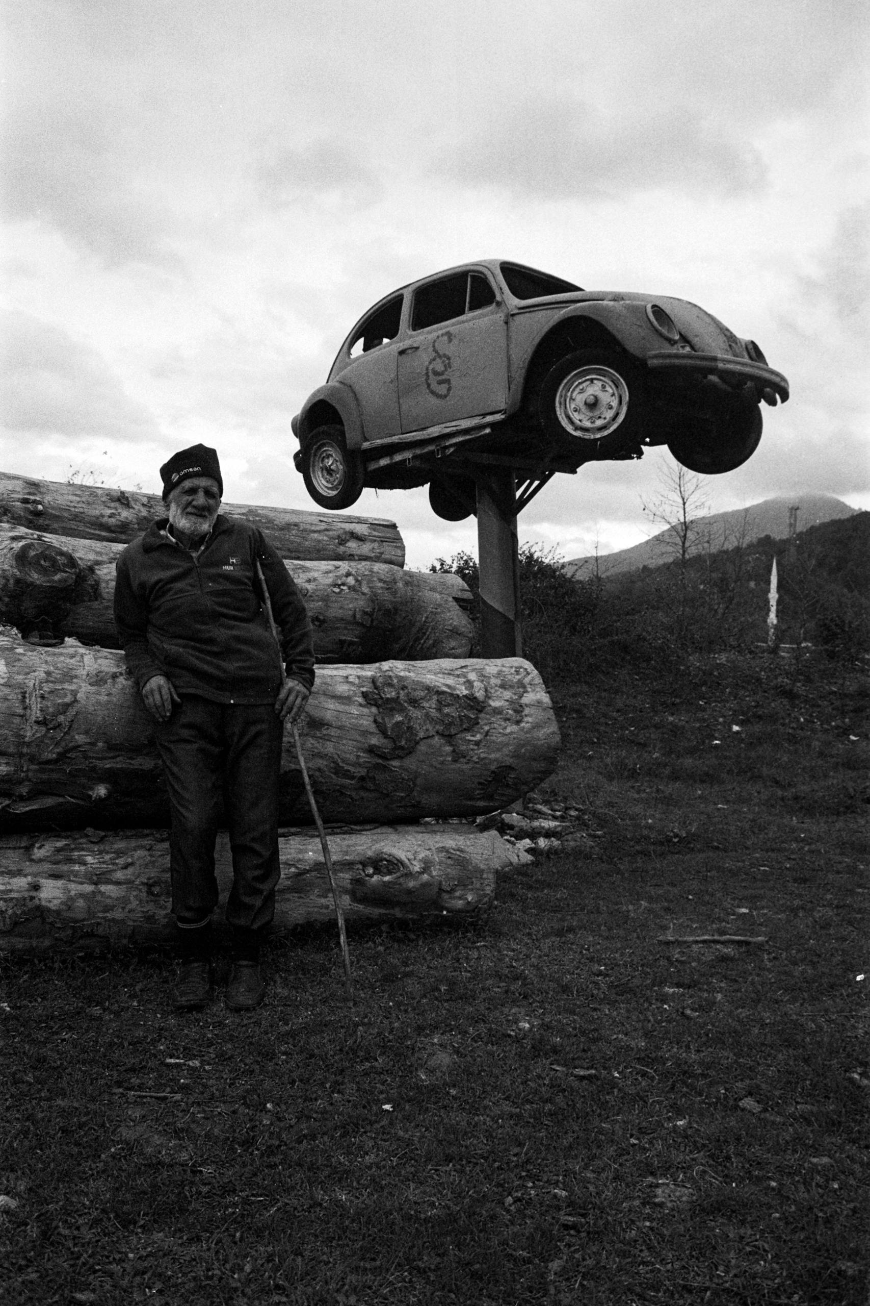 Black and white photo of a man with a vintage car installation outdoors in Bartın, Turkey.