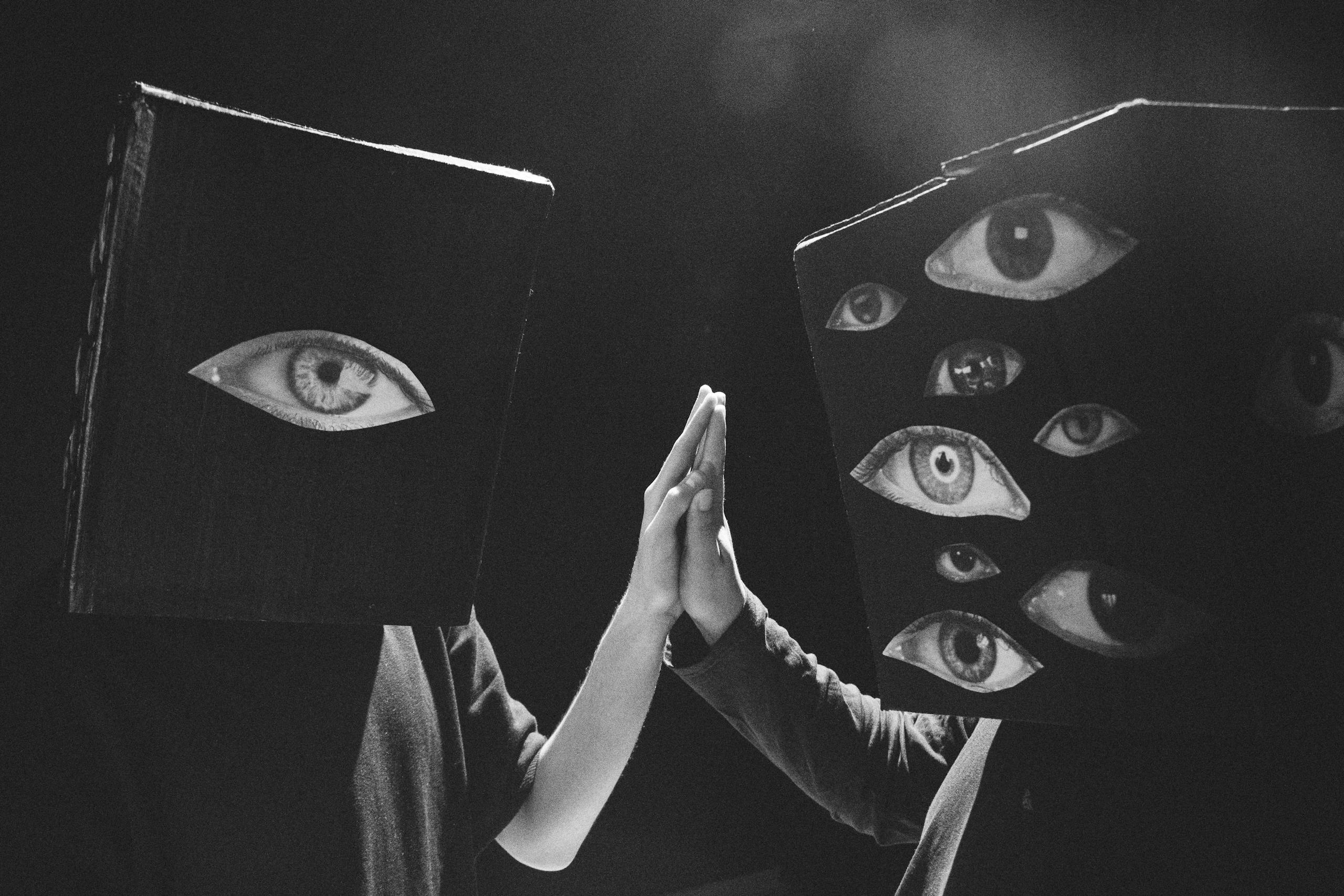 Creative black and white photo of two people with eye-covered cube masks high-fiving.
